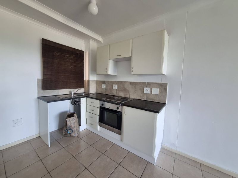 A compact kitchen featuring built-in cabinetry, a tiled backsplash, and integrated oven and hob. The space is functional but requires minor repairs to cabinetry.