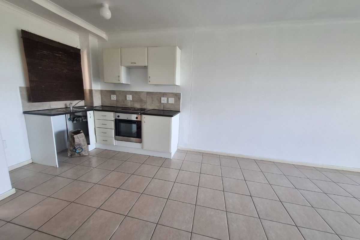 A compact, empty kitchen featuring tiled flooring, built-in cabinetry, an integrated oven and hob, and a tiled backsplash.