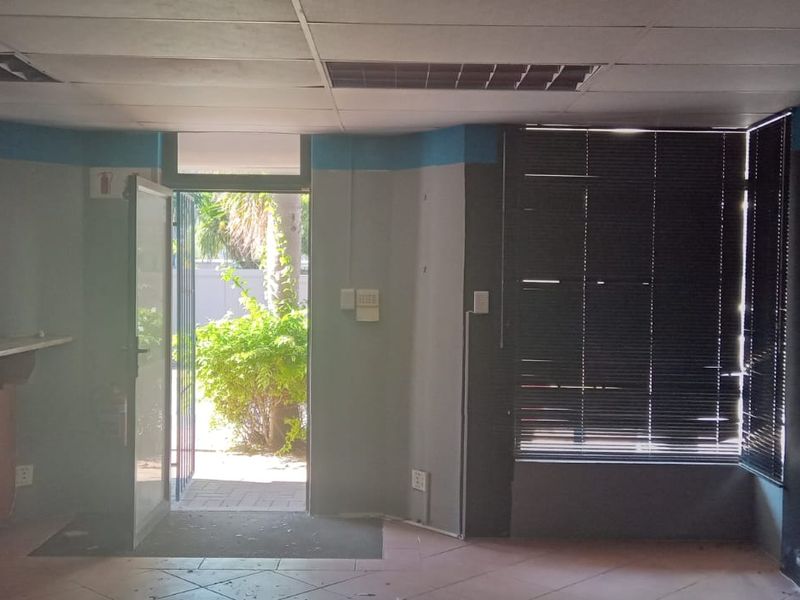 An empty commercial entry area featuring a built-in counter, tiled flooring, drop ceiling, and direct access to an outdoor space.