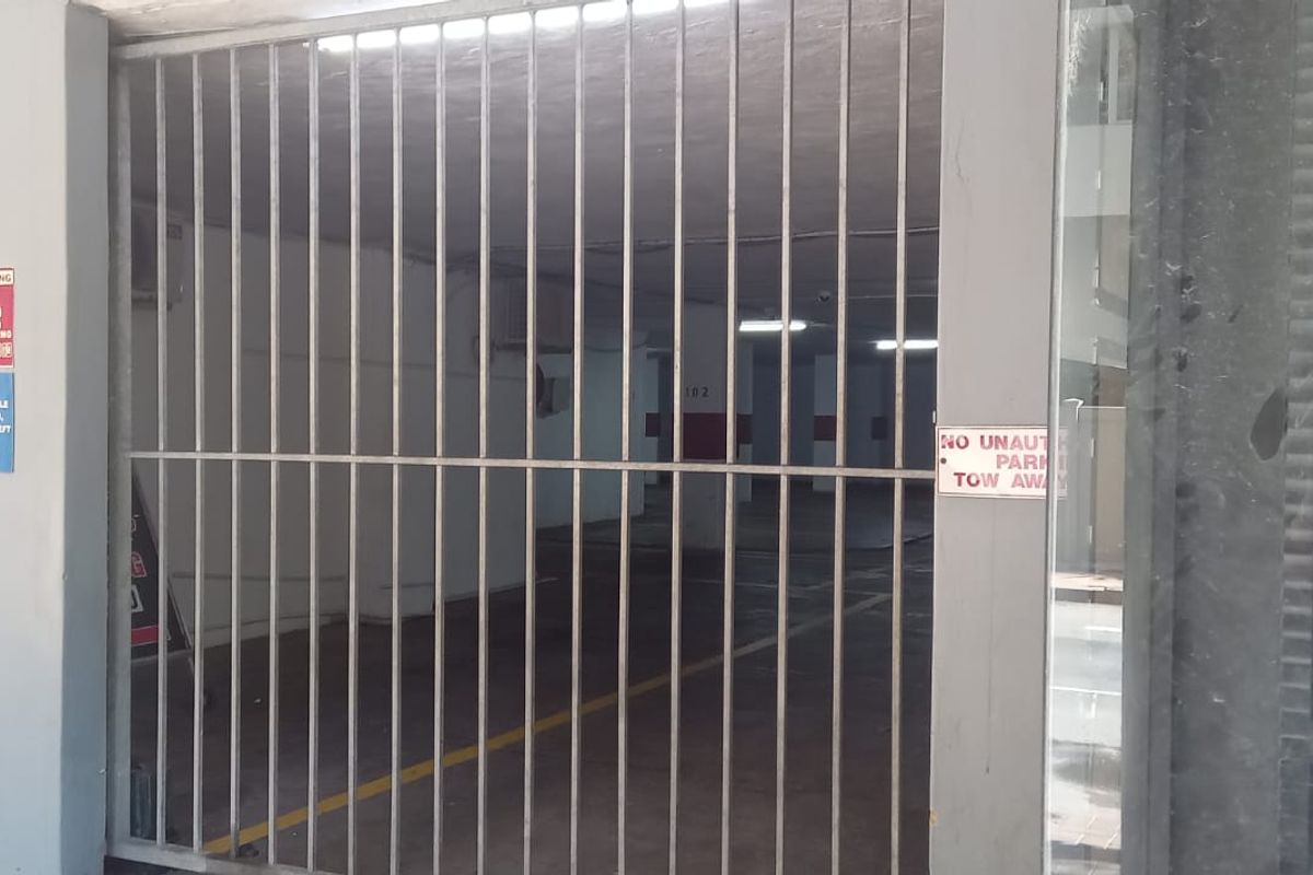 A secure, gated commercial parking garage area with painted concrete walls and overhead lighting.