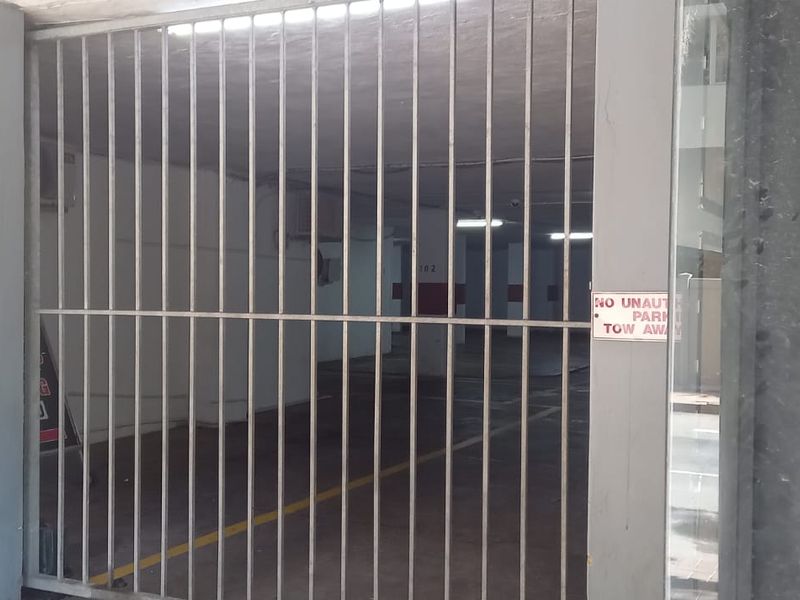A secure, gated commercial parking garage area with painted concrete walls and overhead lighting.