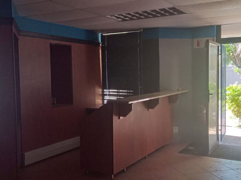 Commercial entry area featuring a built-in reception counter, tiled flooring, and direct access to an outdoor space through a glass door.