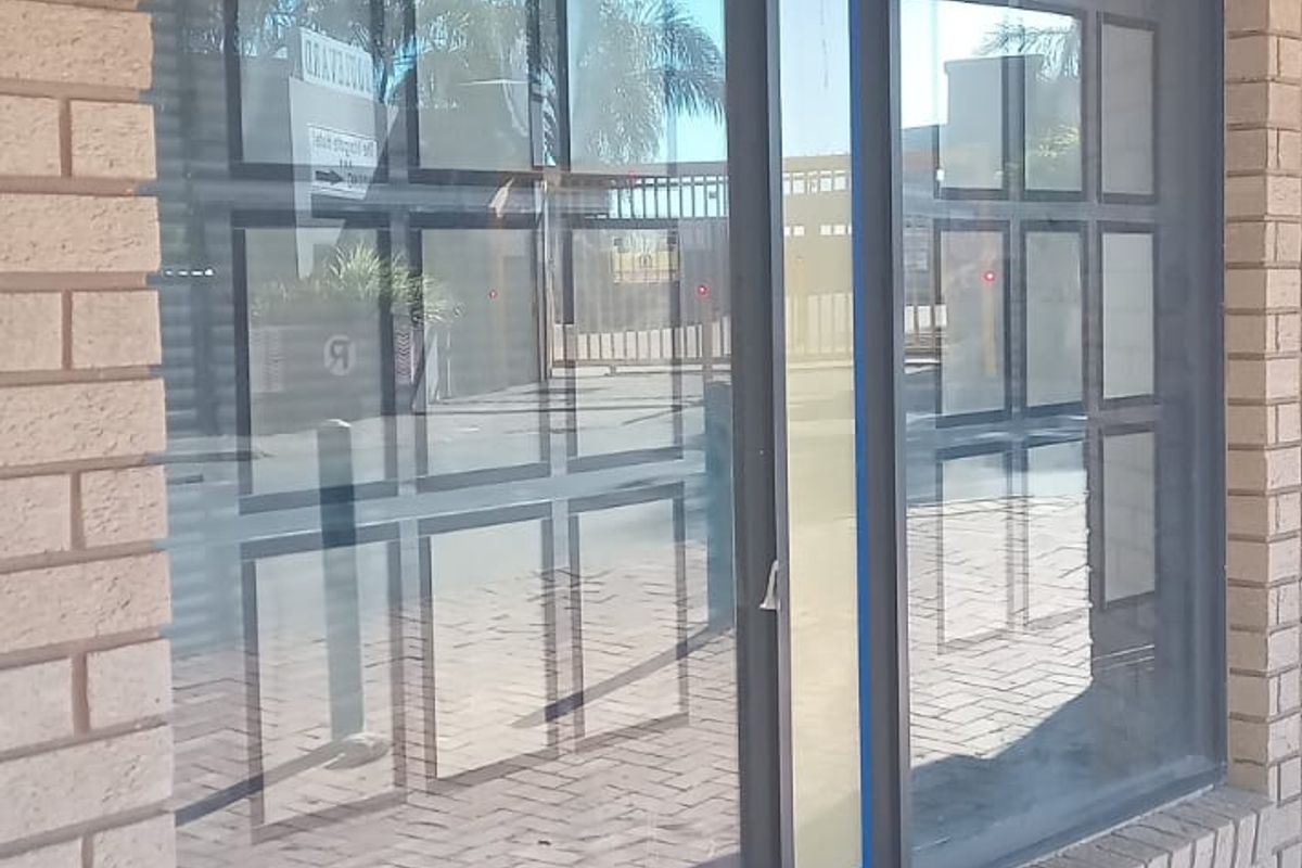 Front exterior view of a commercial property featuring a brick facade and large display windows overlooking a paved walkway.