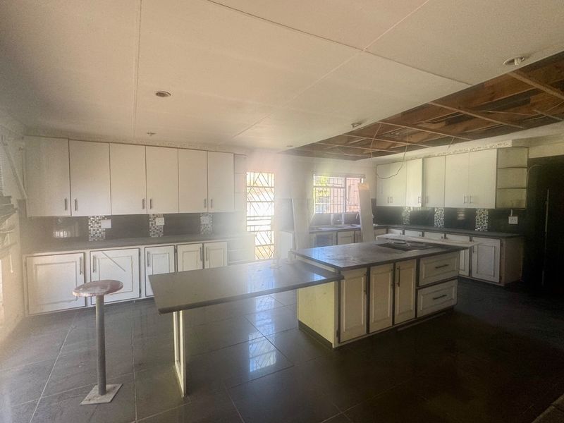 Spacious kitchen featuring extensive cabinetry and a central island, currently requiring ceiling repairs and general refurbishment to restore its functionality and aesthetic appeal.