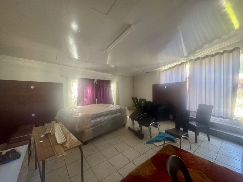 A living area featuring tiled flooring and fluorescent lighting, currently in need of cosmetic updates and ceiling repairs.