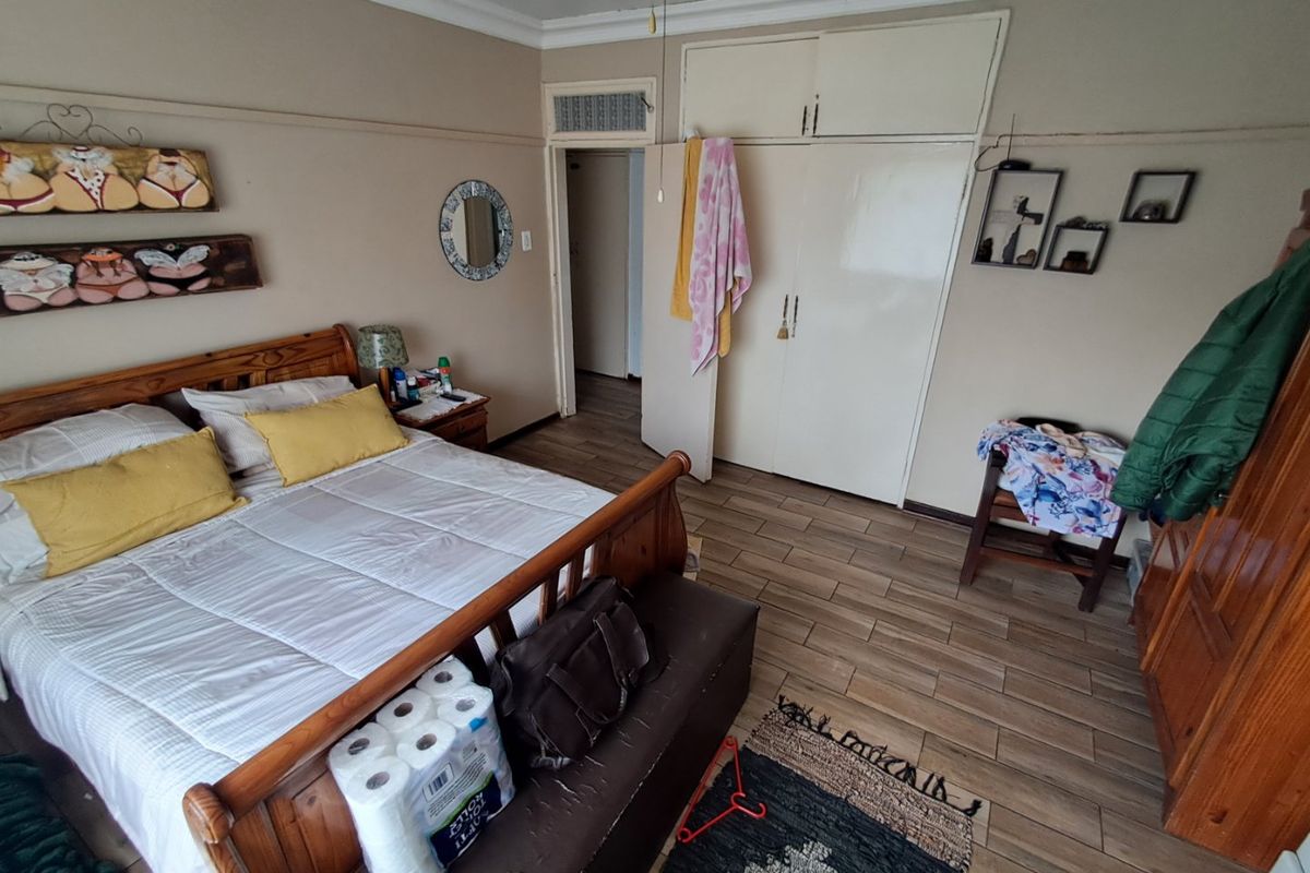 A bedroom featuring wood-look tile flooring, built-in storage cupboards, and crown molding detail.