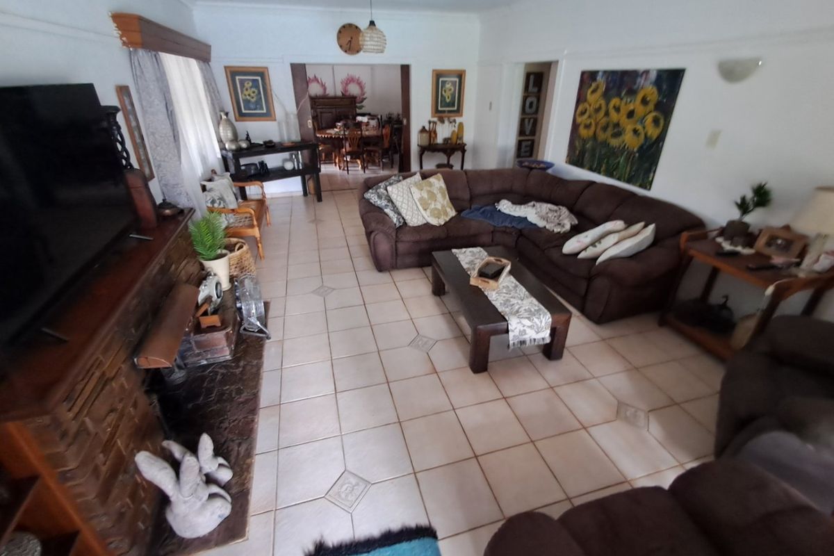Spacious living room featuring a prominent brick fireplace, tiled flooring, and an open-plan layout connecting to the adjacent dining area.