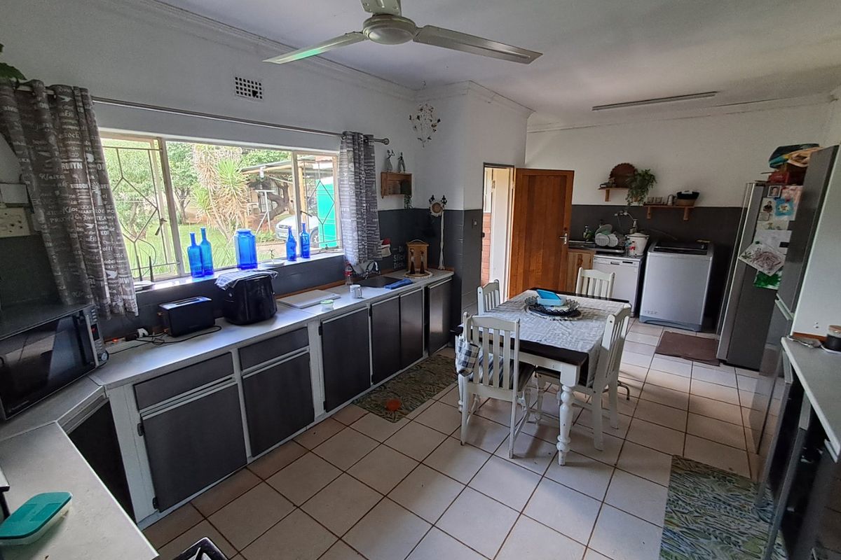 Spacious kitchen featuring tiled flooring, built-in cabinetry, a ceiling fan, and an integrated dining area with direct access to the rear garden.