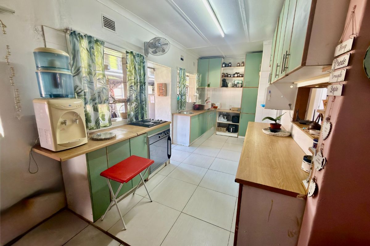 A functional kitchen featuring light green cabinetry, wood-look countertops, tiled flooring, and integrated oven and hob.