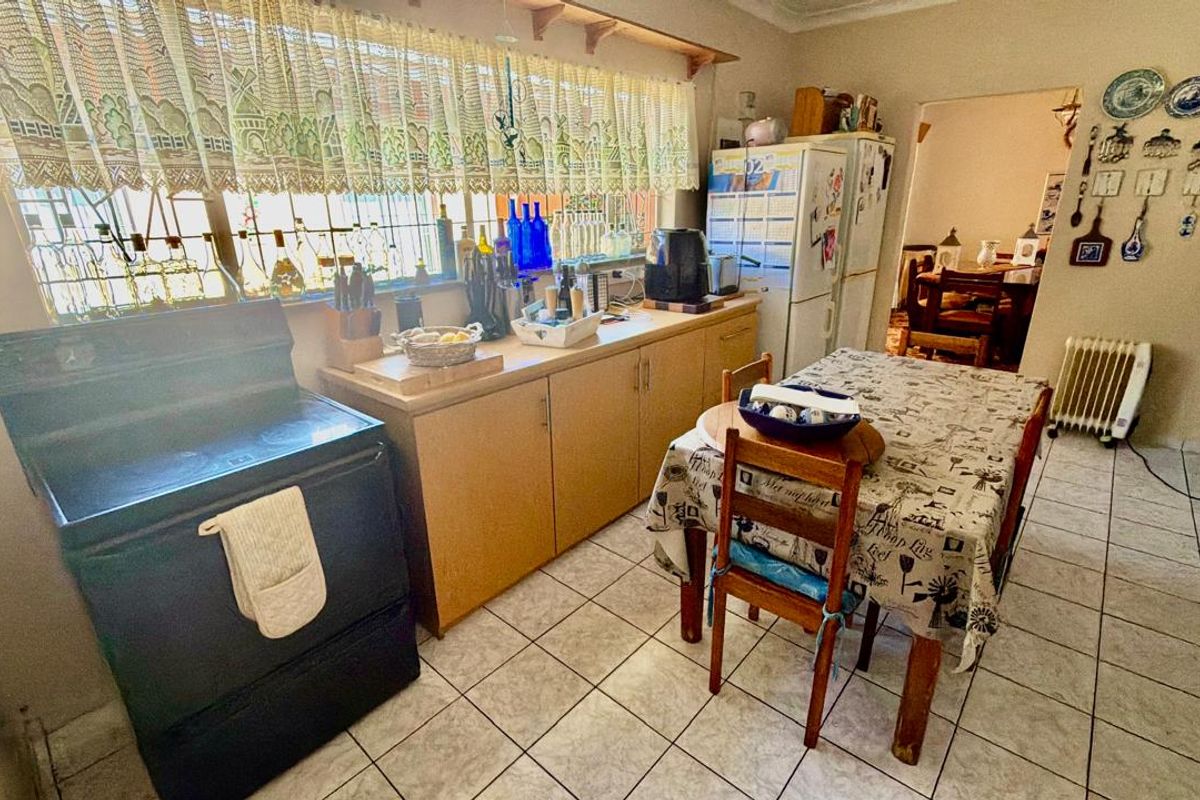 A functional kitchen featuring tiled flooring, built-in cabinetry, and a freestanding stove, with security bars installed on the window.