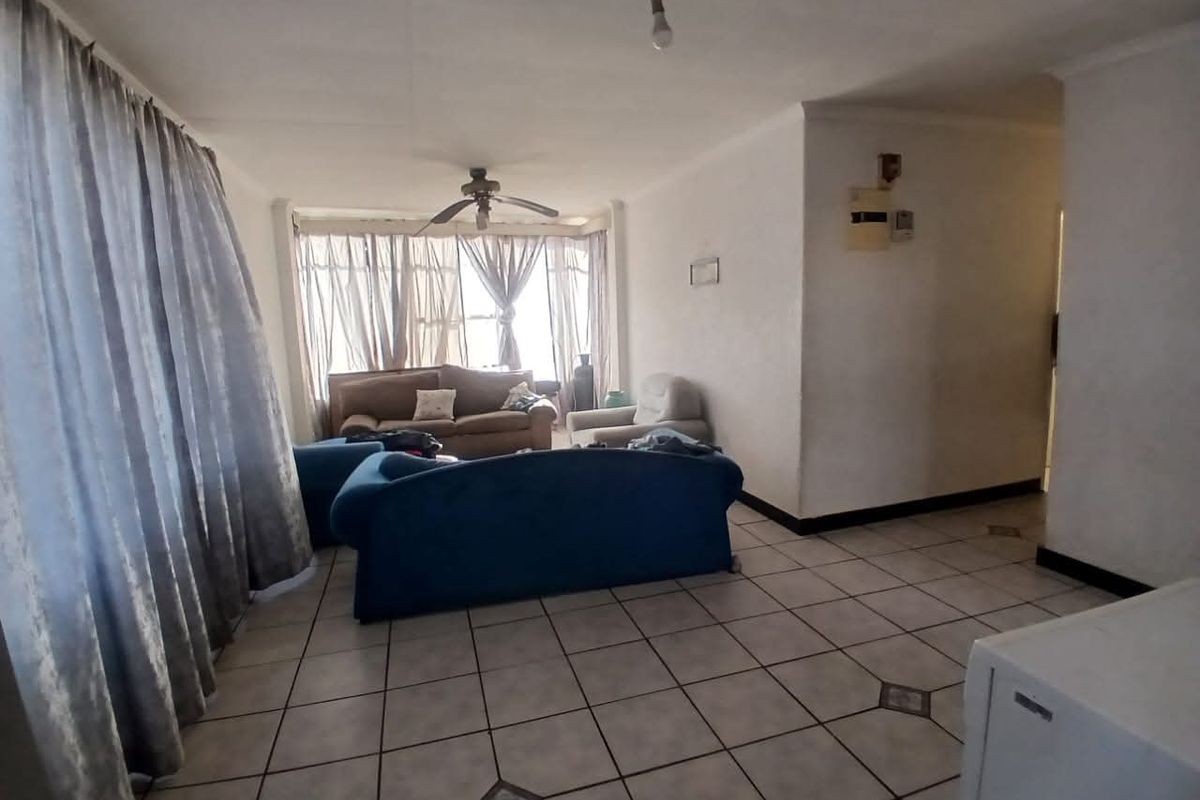 A living room area featuring tiled flooring and a ceiling fan, requiring cosmetic updates to improve the overall aesthetic and finish.