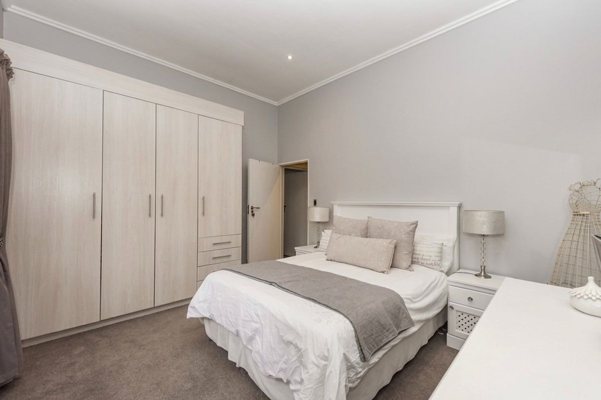 A well-maintained bedroom featuring neutral grey walls, plush carpeting, and extensive built-in cabinetry for ample storage.