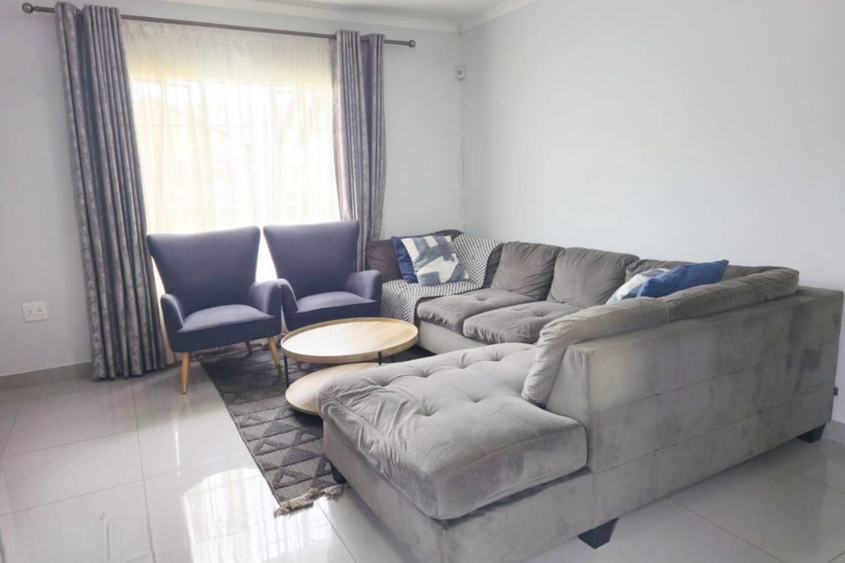 A bright and spacious living room featuring neutral tiled flooring and large windows with installed curtain rods.