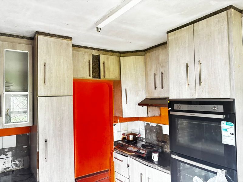 Kitchen featuring light wood-grain cabinetry, built-in oven, and gas hob, requiring cosmetic updates to wall finishes and backsplash tiling.