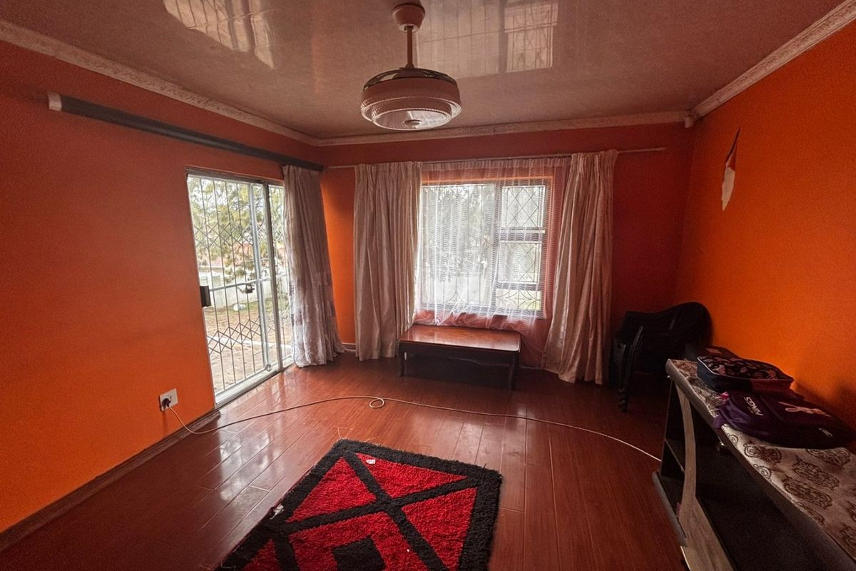 A living room featuring laminate flooring, a ceiling fan, and access to the exterior via a sliding security door.