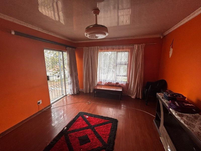 A living room featuring laminate flooring, a ceiling fan, and access to the exterior via a sliding security door.