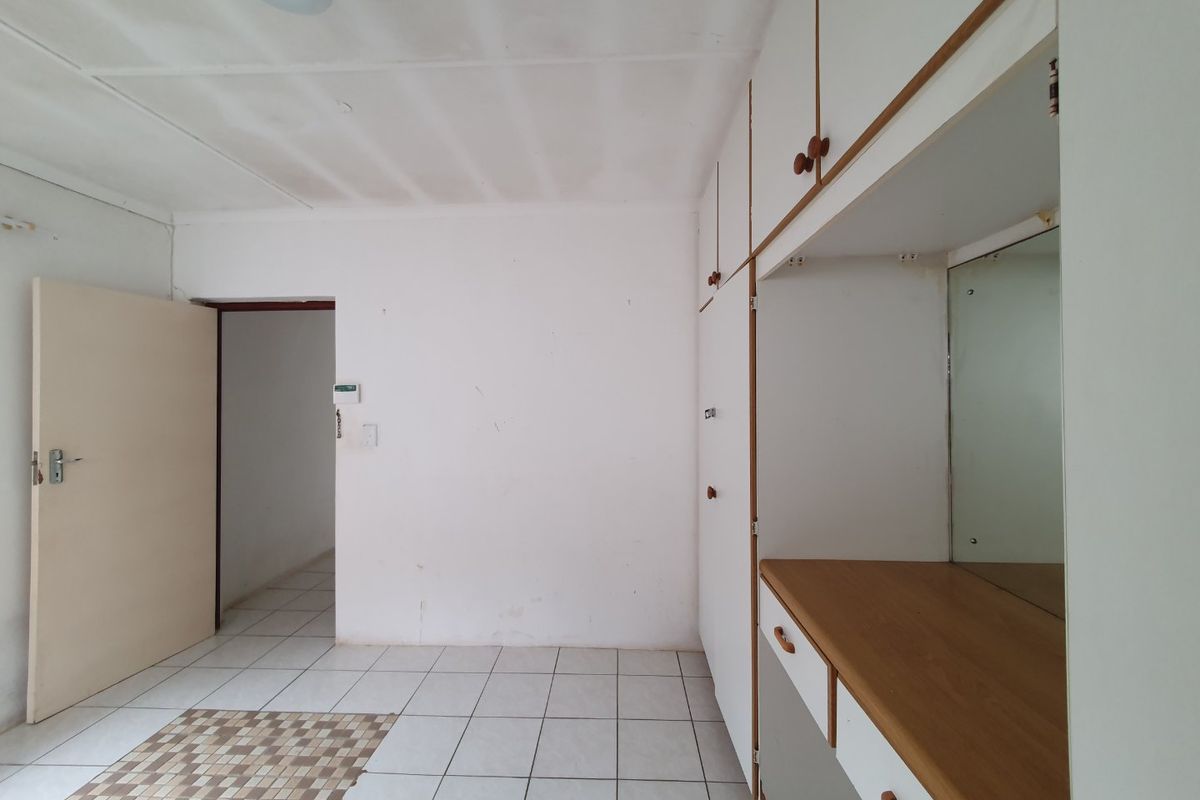 A vacant bedroom featuring built-in cabinetry with a vanity area, tiled flooring, and a neutral interior finish.