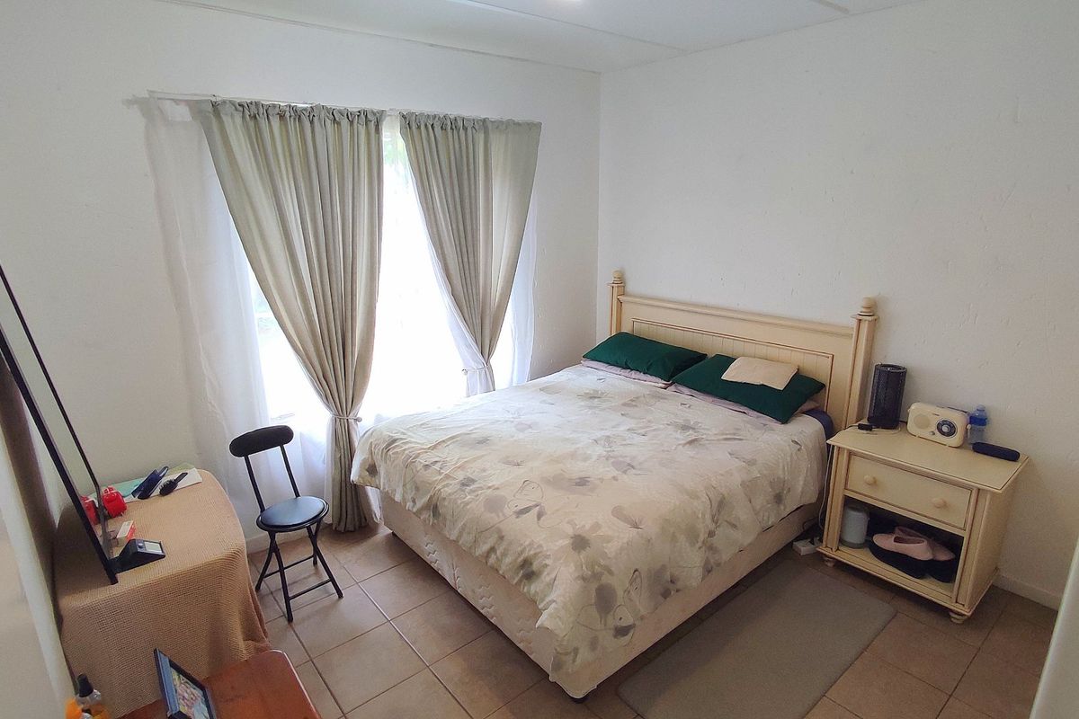 A functional bedroom featuring tiled flooring and large windows with installed curtain tracks, offering a neutral space ready for personalization.