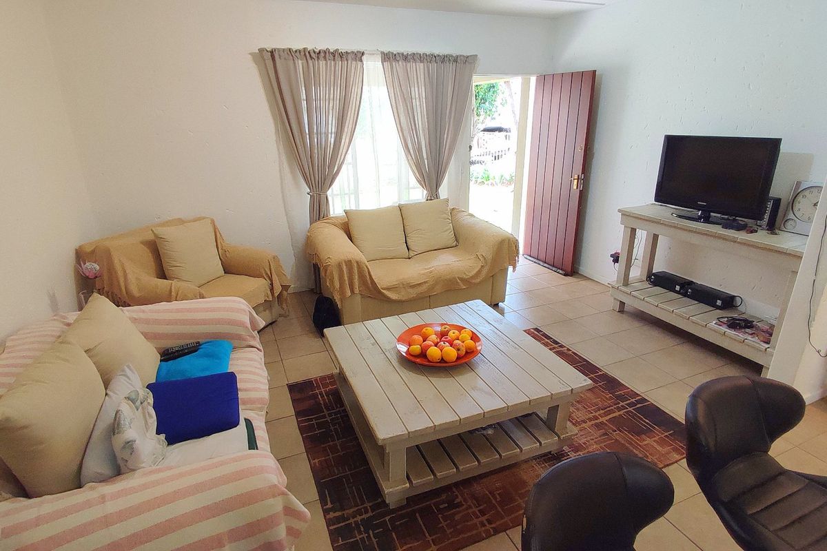 A functional living room featuring tiled flooring and direct access to the exterior through a timber door.