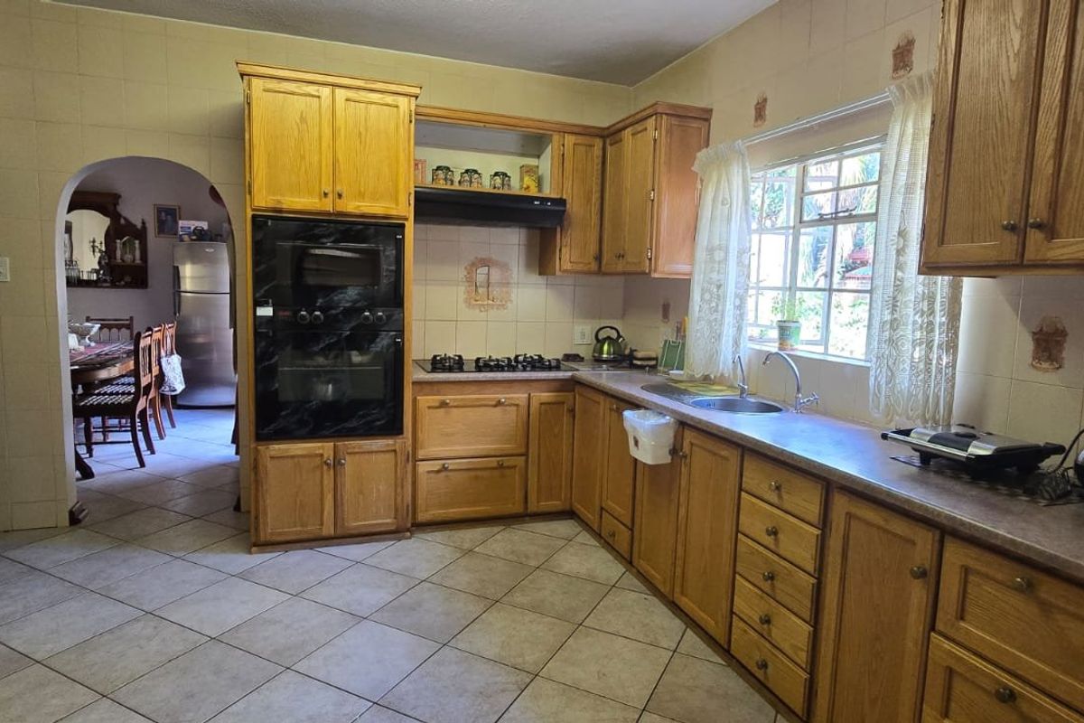 A functional kitchen featuring traditional wooden cabinetry, built-in oven, gas hob, and tiled flooring, offering a classic layout with potential for modern updates.