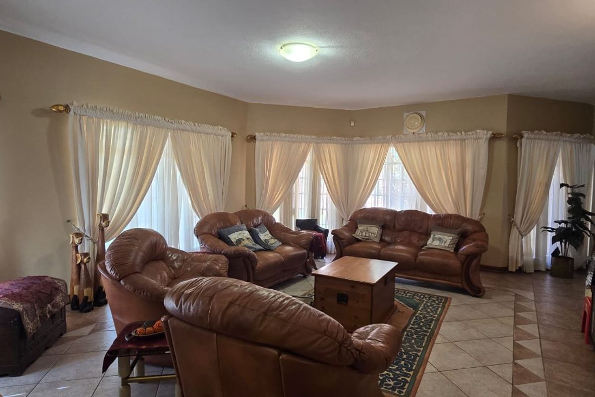 Spacious living room featuring tiled flooring and large windows with curtain treatments, offering a comfortable and functional layout for relaxation.