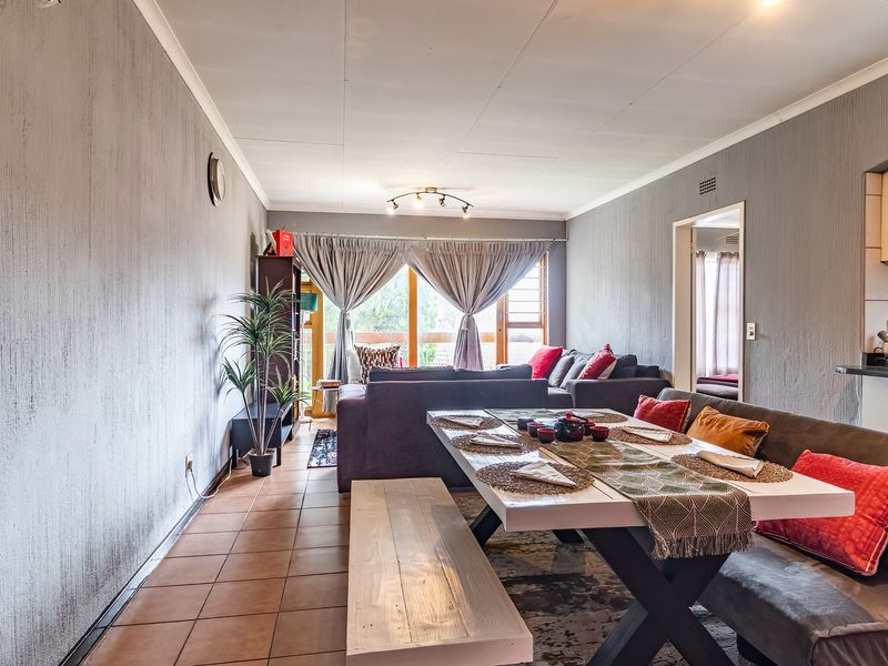Open-plan living and dining area featuring tiled floors, textured walls, and direct access to a balcony, adjacent to a functional kitchen space.