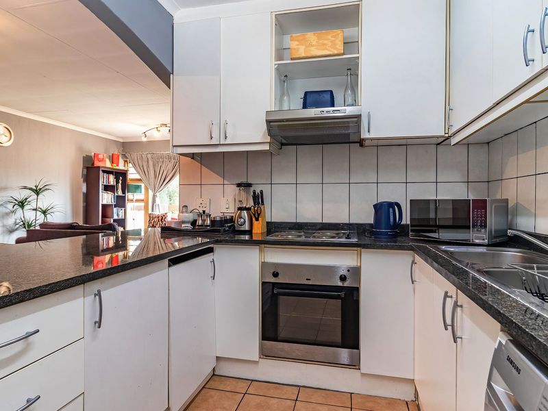 Open-plan kitchen featuring granite countertops, built-in oven, electric hob, and ample cabinetry, seamlessly flowing into the adjacent living area.