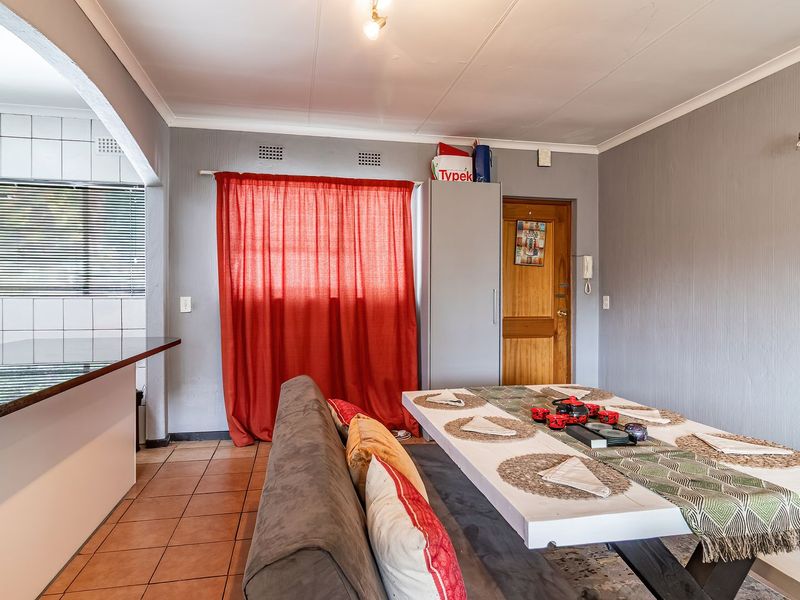 Open-plan living and dining area featuring tiled flooring, a breakfast bar, and direct access to the kitchen space.