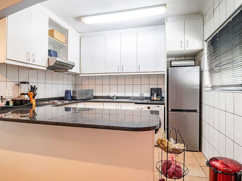 A functional kitchen featuring white cabinetry, granite countertops, tiled backsplash, and a breakfast bar, offering a practical layout for daily meal preparation.