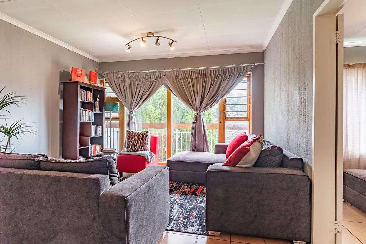 A comfortable living room featuring tiled flooring, neutral wall finishes, and a large sliding glass door providing access to an outdoor balcony area.