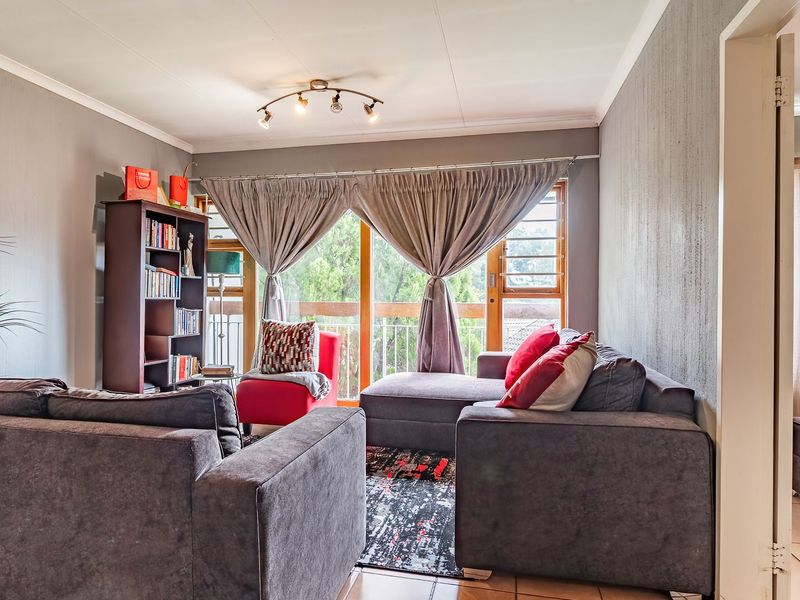 A comfortable living room featuring tiled flooring, neutral wall finishes, and a large sliding glass door providing access to an outdoor balcony area.