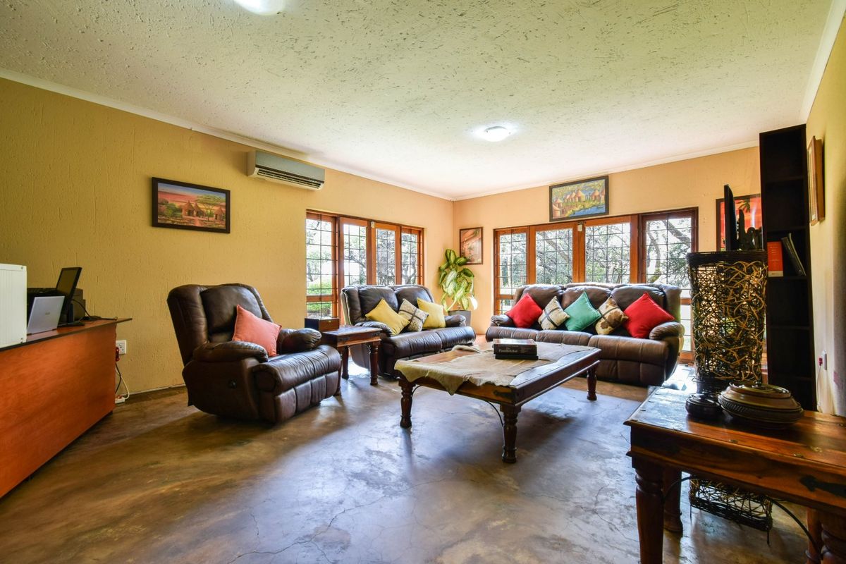 Spacious living room featuring polished concrete floors, air conditioning, and large timber-framed windows providing natural light and garden views.