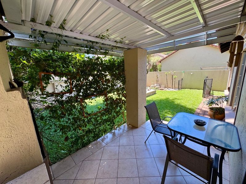 Covered patio area featuring tiled flooring, a corrugated metal roof, and a trellis screen overlooking the rear garden.