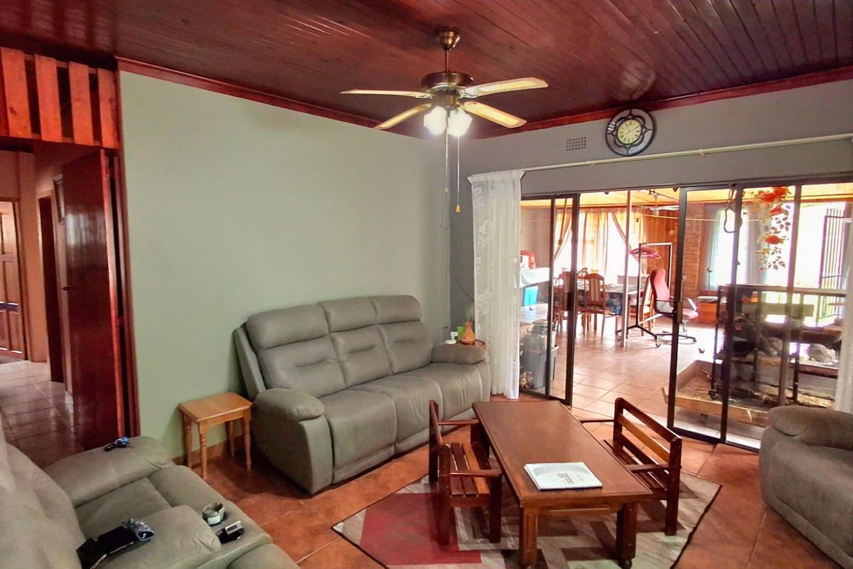 Spacious living room featuring a timber ceiling, ceiling fan, and large sliding glass doors that provide access to an adjoining room.
