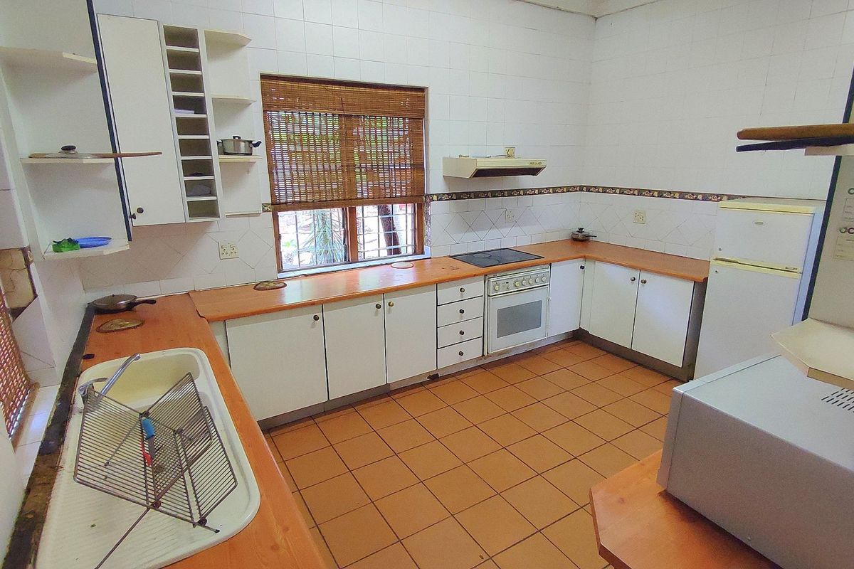 A functional kitchen featuring tiled flooring, laminate countertops, built-in cabinetry, and integrated cooking appliances, offering potential for a modern renovation.