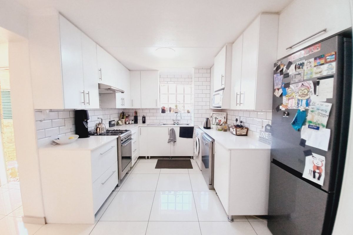 Modern galley-style kitchen featuring white cabinetry, subway tile backsplash, gas stove, and sleek porcelain floor tiles.