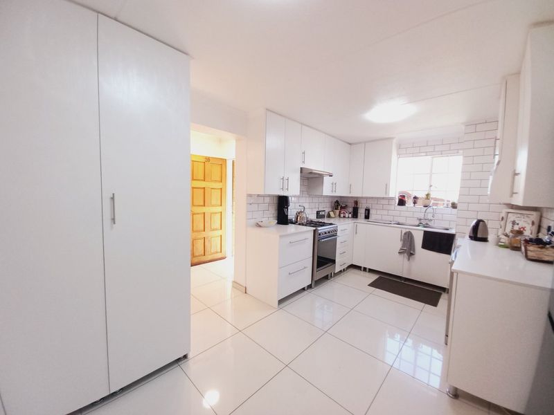 Modern kitchen featuring white cabinetry, subway tile backsplash, gas stove with extractor fan, and polished porcelain floor tiles.