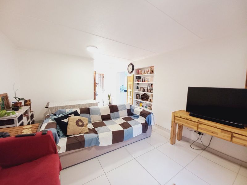 A living room featuring white tiled flooring and a built-in wall shelving unit, providing a functional and neutral space.