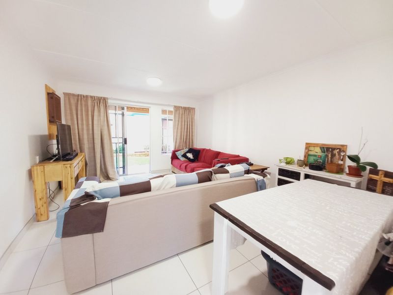 A bright living room featuring tiled flooring and a sliding glass door providing access to the outdoor area.