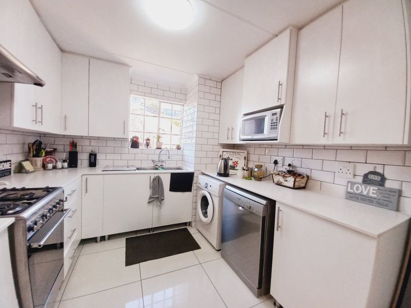 A bright, functional kitchen featuring white cabinetry, subway tile backsplash, stainless steel appliances, and tiled flooring, offering a clean and modern aesthetic.