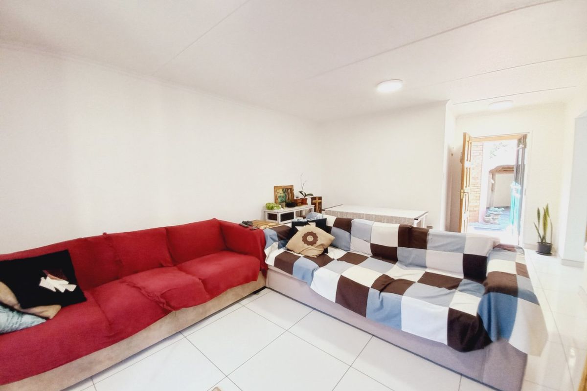 A bright living room featuring white tiled flooring and direct access to an outdoor area, providing a functional and open living space.