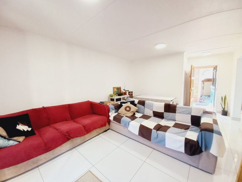 A bright living room featuring white tiled flooring and direct access to an outdoor area, providing a functional and open living space.