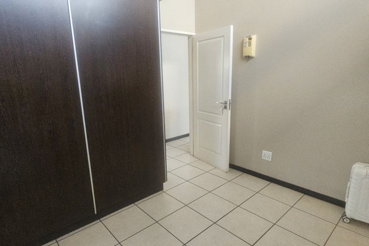 A bedroom featuring built-in cupboards, tiled flooring, and an intercom system, offering a clean and functional space.
