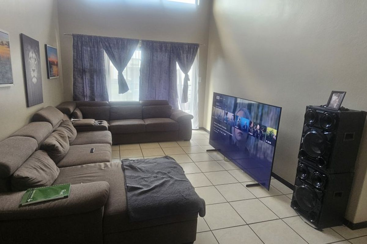 A spacious living room featuring tiled flooring and high ceilings, offering a comfortable area for relaxation and entertainment.