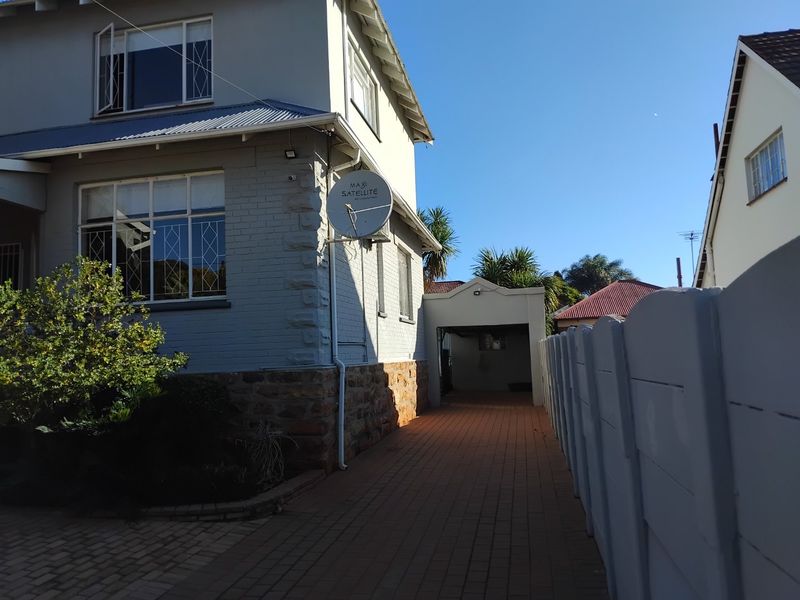 Side view of the property showing a paved driveway, brick and stone facade, and a carport structure.