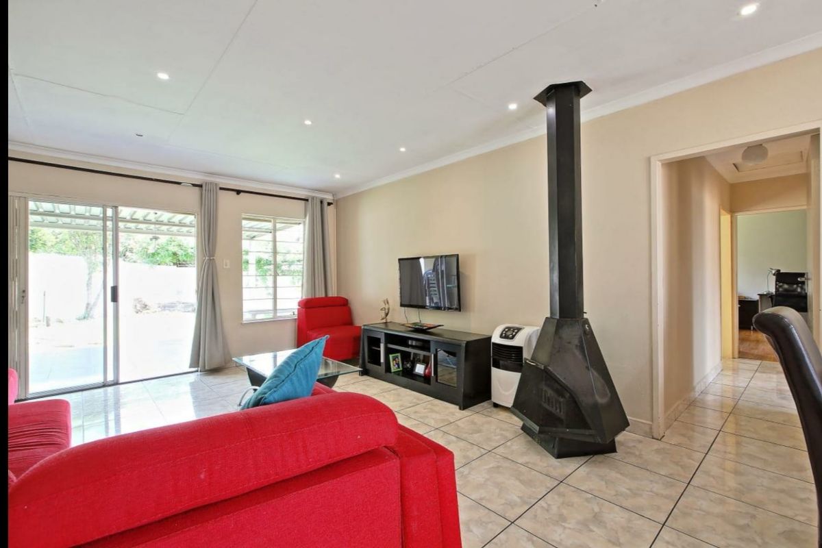 Spacious living room featuring tiled flooring, a prominent freestanding fireplace, and sliding glass doors providing access to the outdoor area.