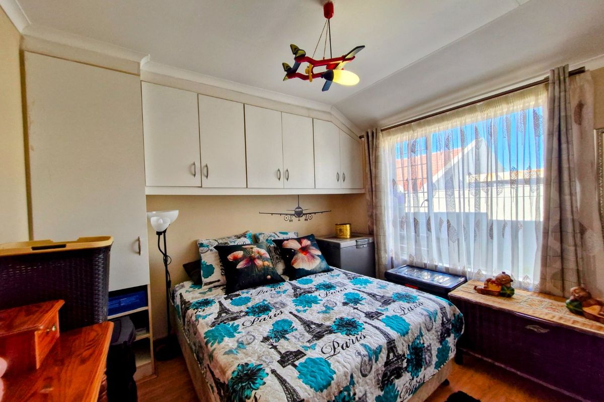 A compact bedroom featuring built-in overhead cabinetry and laminate flooring, offering functional storage space.