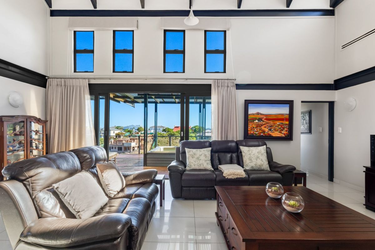 Spacious living room featuring high vaulted ceilings with exposed beams, large sliding doors opening to a deck, and abundant natural light from clerestory windows.