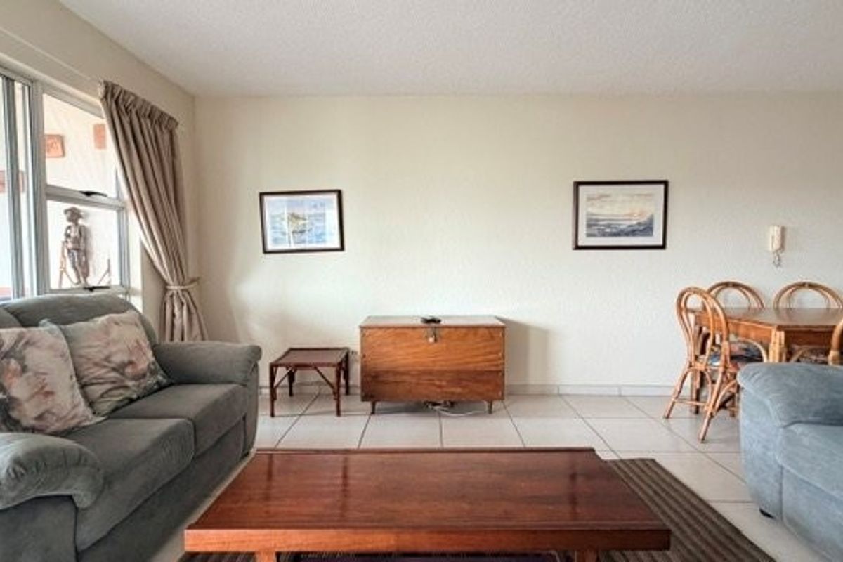 A spacious living area featuring tiled flooring and a large sliding glass door providing access to the outdoor space.
