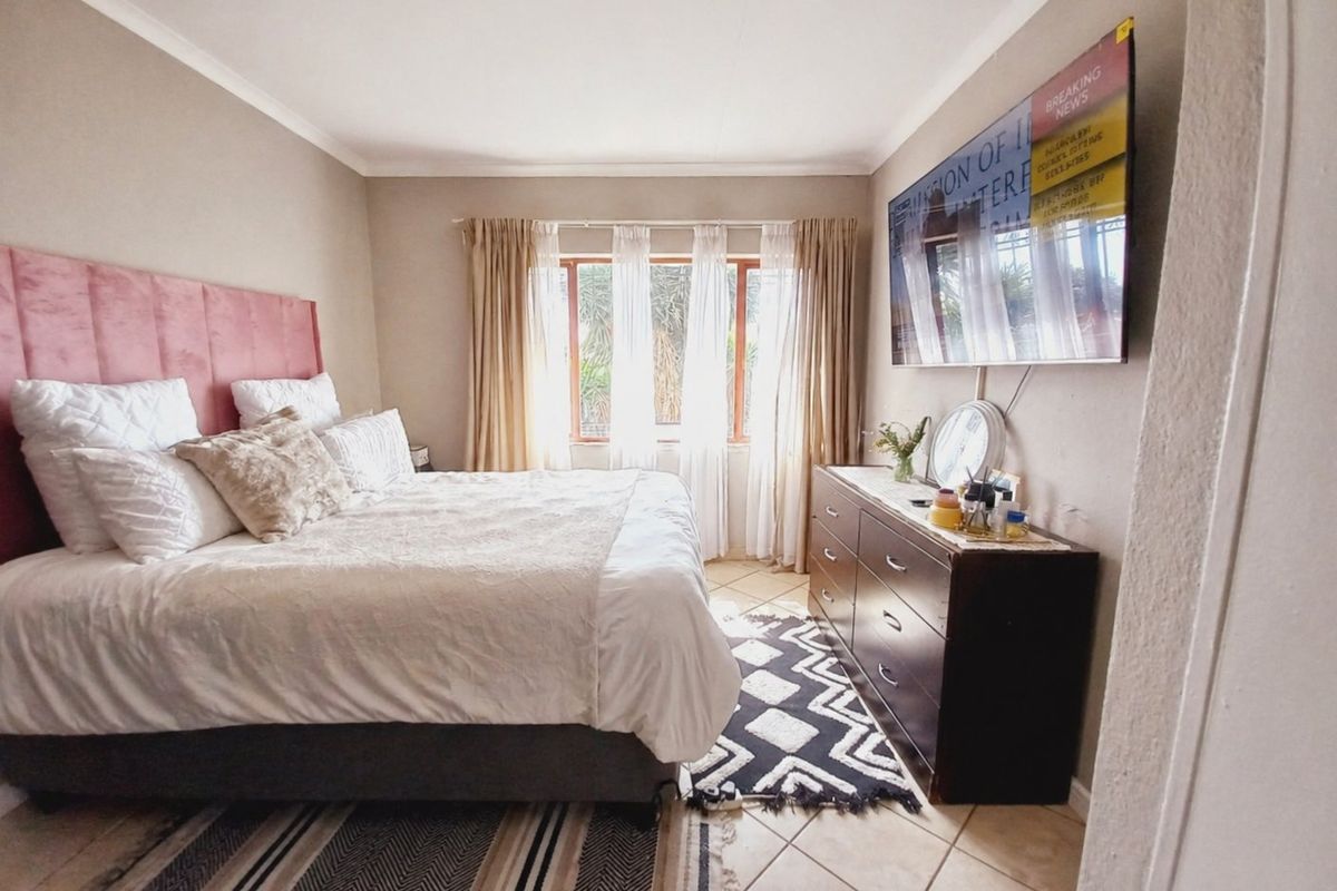 A well-lit bedroom featuring tiled flooring, coved ceilings, and a large window, providing a comfortable and functional living space.